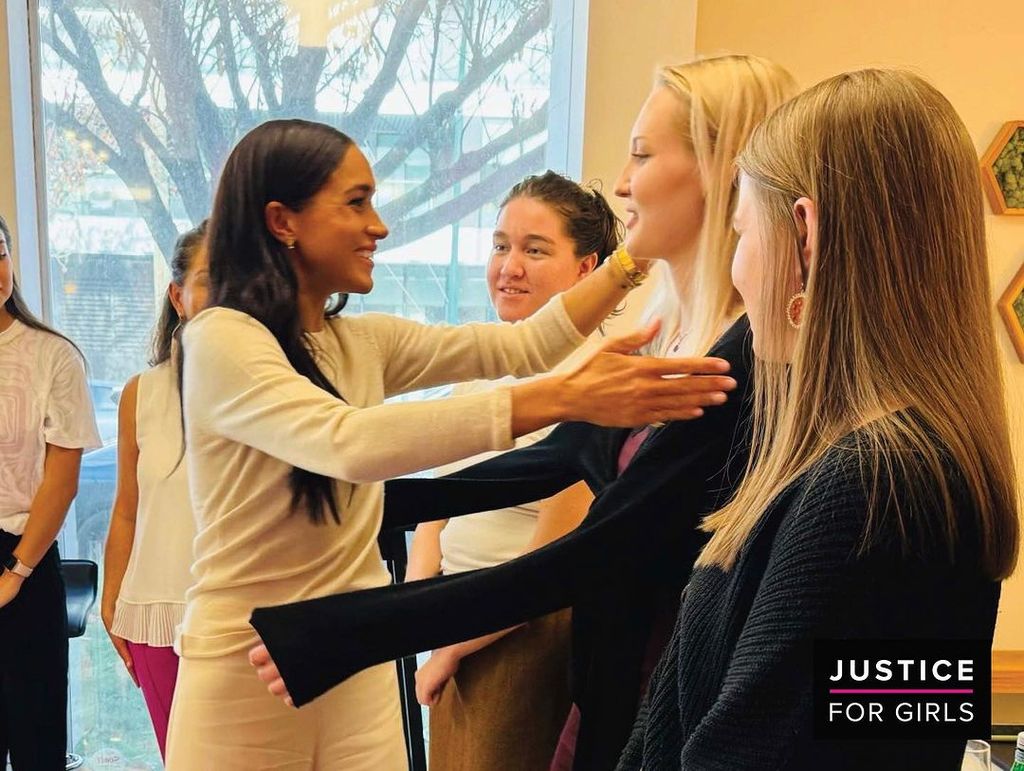 Meghan reaches out to hug the girls at her recent visit to Justice for Girls charity