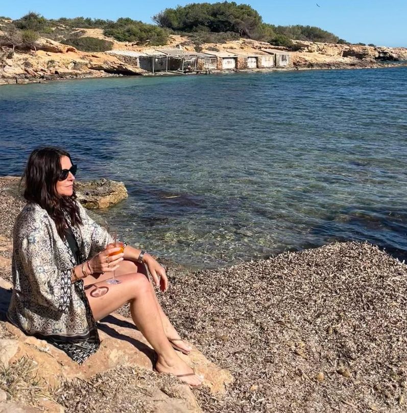 Ginny Buckley with a glass of wine on a beach