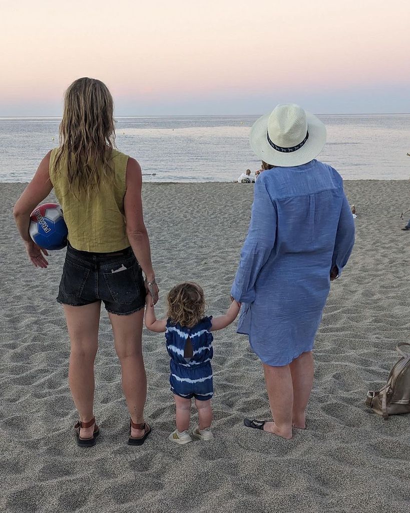 Helen Skelton in shorts holding hands with her daughter on the beach