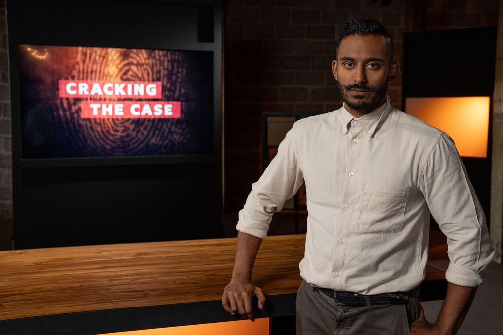 A man with a pale shirt leans on a table