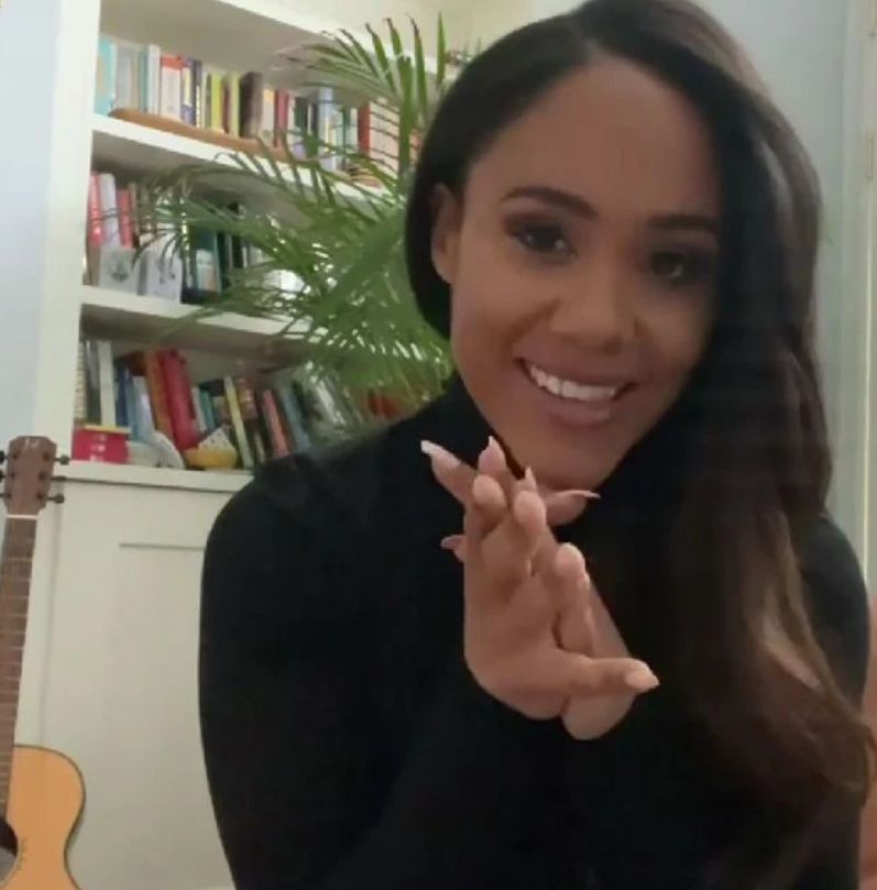 Alex Scott with a bookshelf and guitar in the background