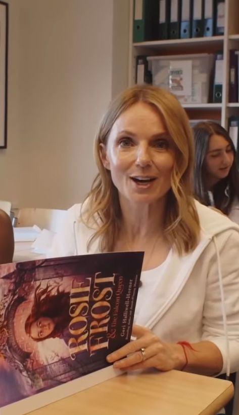 Geri Halliwell-Horner in a classroom with a copy of her book