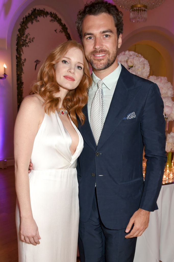 Jessica Chastain in a white dress leaning on the shoulder of her husband