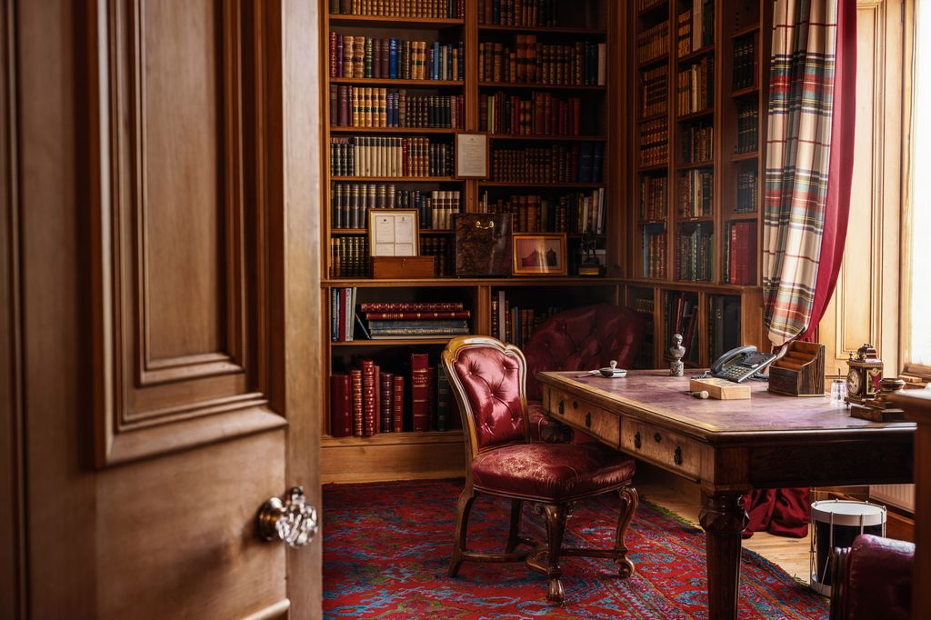 A library with bookshelves and a desk with a red chair