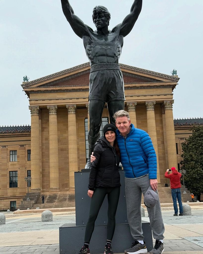 husband and wife posing in front of statue