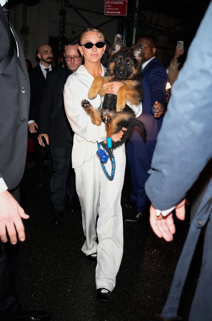 Sydney Sweeney looking ethereal in all white suit while holding her puppy sully