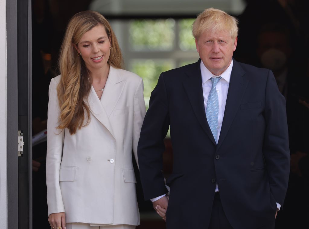Boris Johnson in a blue suit and his wife Carrie in a white suit