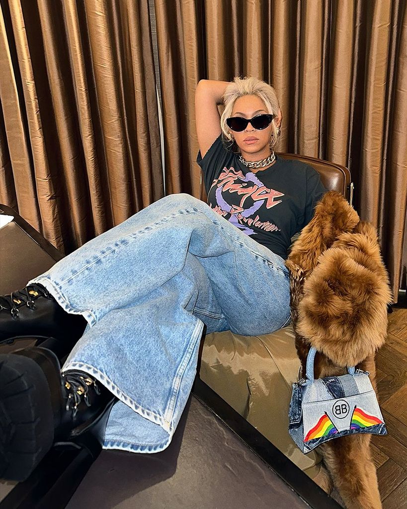 Beyoncé poses sat down in jeans, Prince t-shirt, fur coat