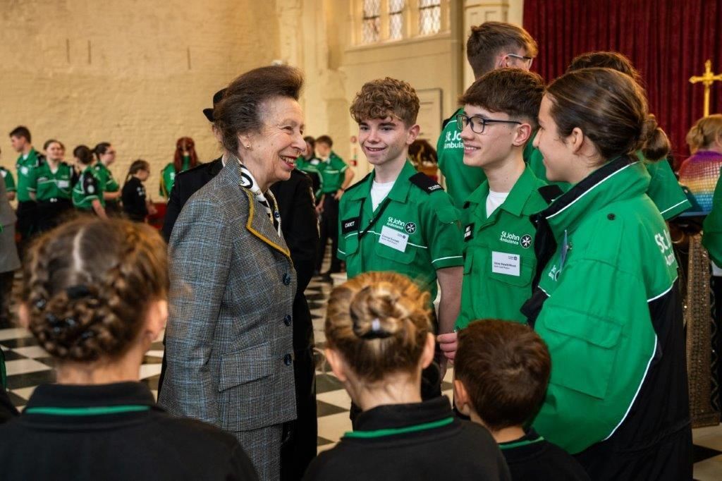 Anne in a tweed jacket talking to young ambulance volunteersv