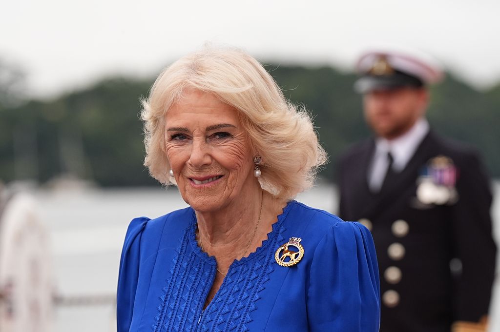 Queen Camilla smiling in a bold blue dress