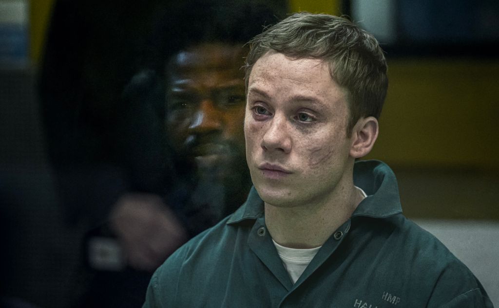 Man with bruised face in grey jumpsuit