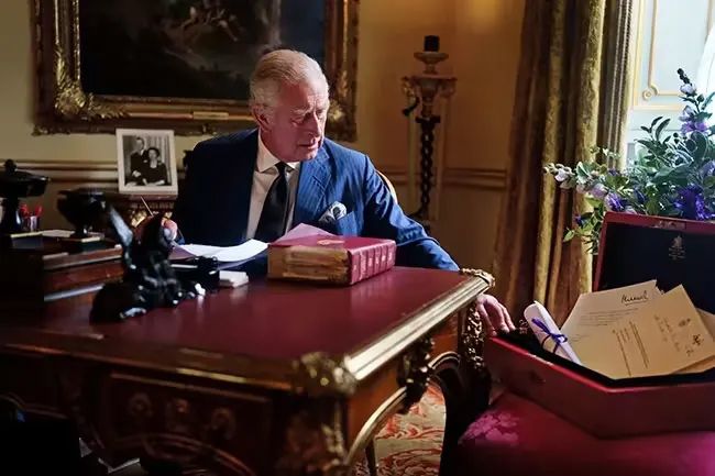 king charles at work on desk at buckingham palace