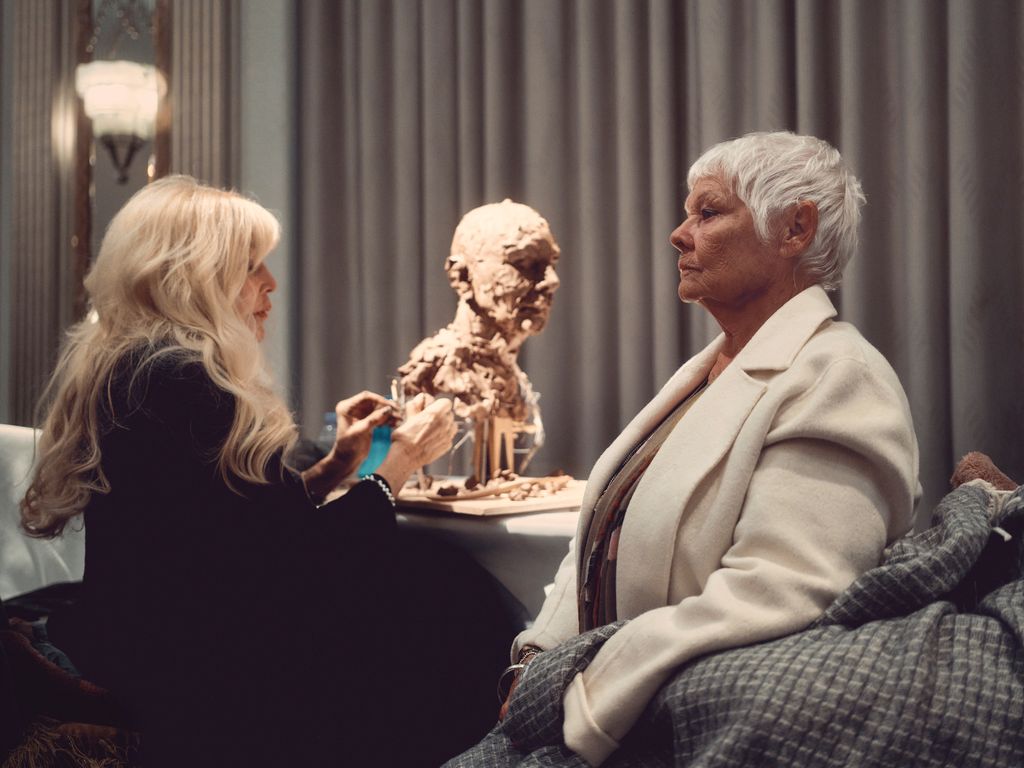 Dame Judi Dench looking serious as a woman creates a sculpture of her