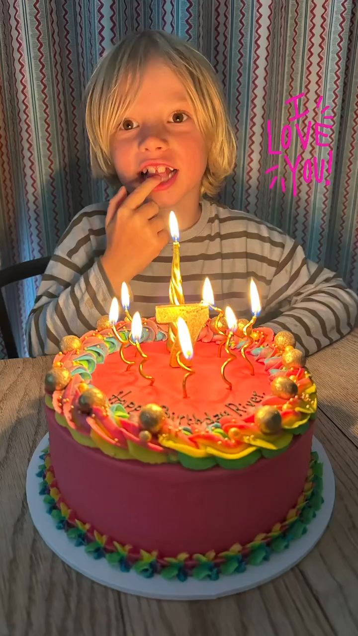 River Oliver behind a pink and rainbow birthday cake