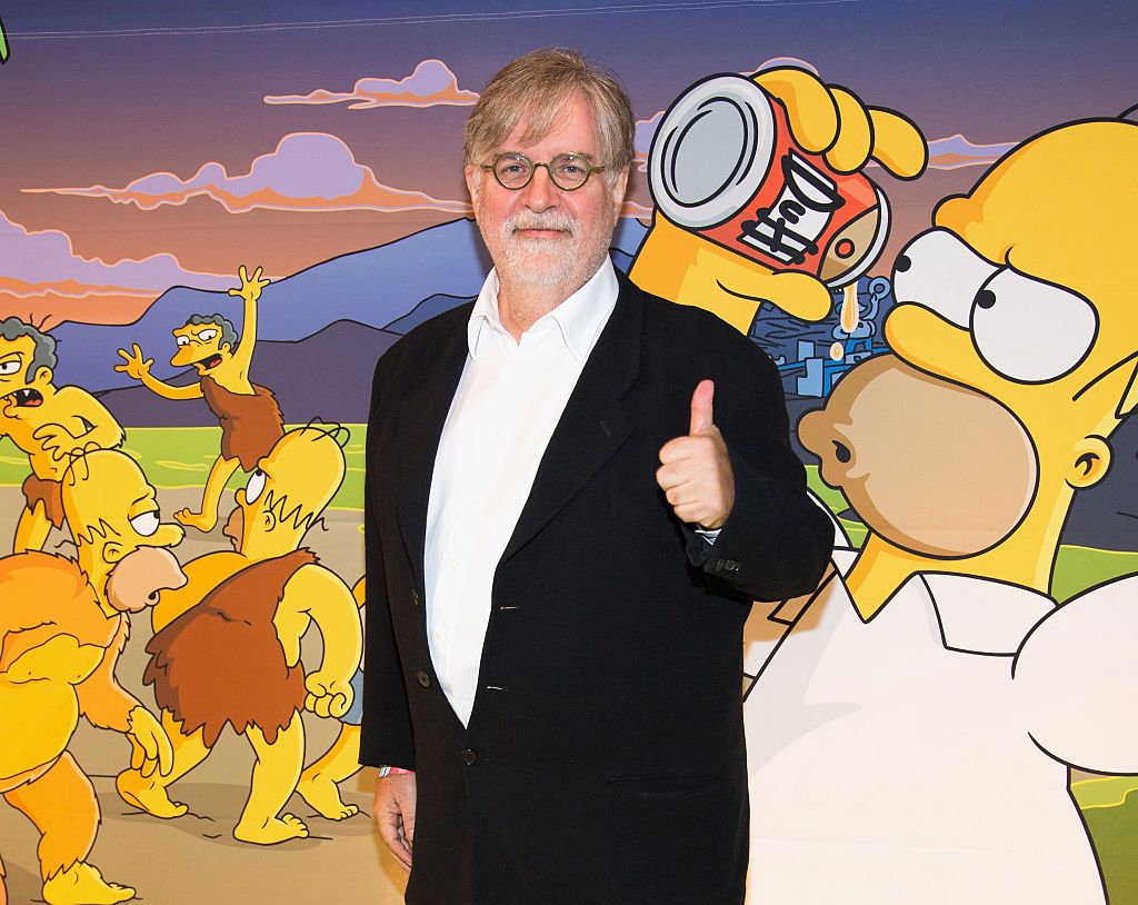 Matt Groening poses in front of a Simpsons background