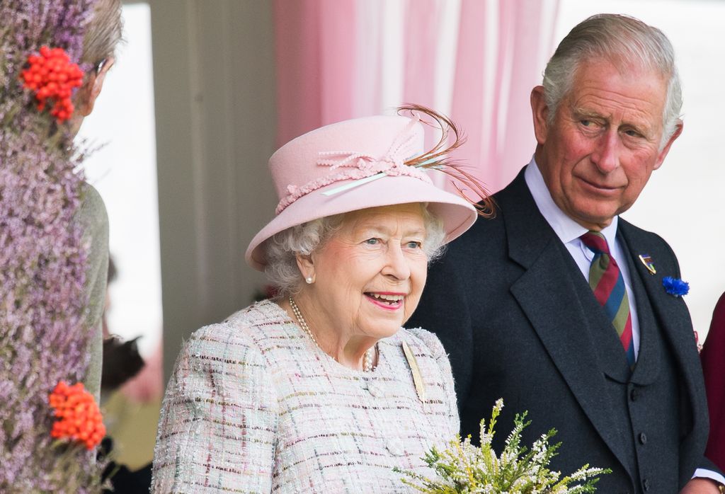 Wearing a suit, Charles looks on at his mother, the Queen, with great admiration
