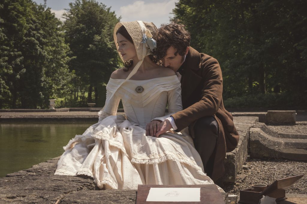 woman and man in period clothing sittin by lake