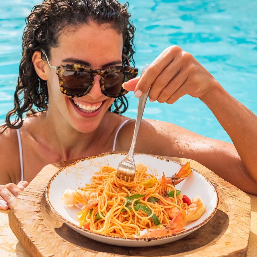 woman wearing sunglasses eating pasta at nikki beach