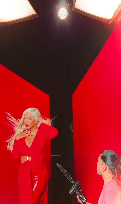 Christina Aguilera posing in red outfit while wind blows her hair
