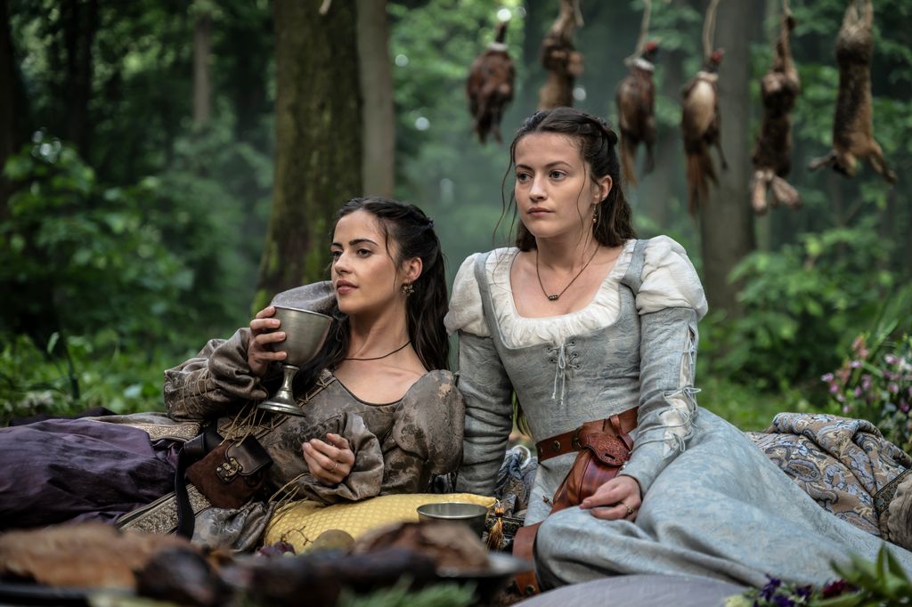 two women in period clothing sitting in woodland