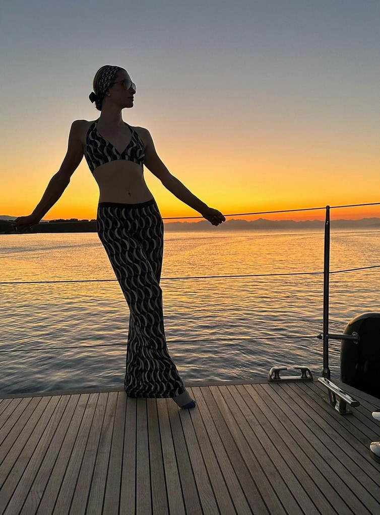 Photo shared by Paris Hilton on Instagram August 2023 from her vacation aboard a luxury yacht throughout Greece, where she is in a halterneck bikini and printed pants, posing at sunset.