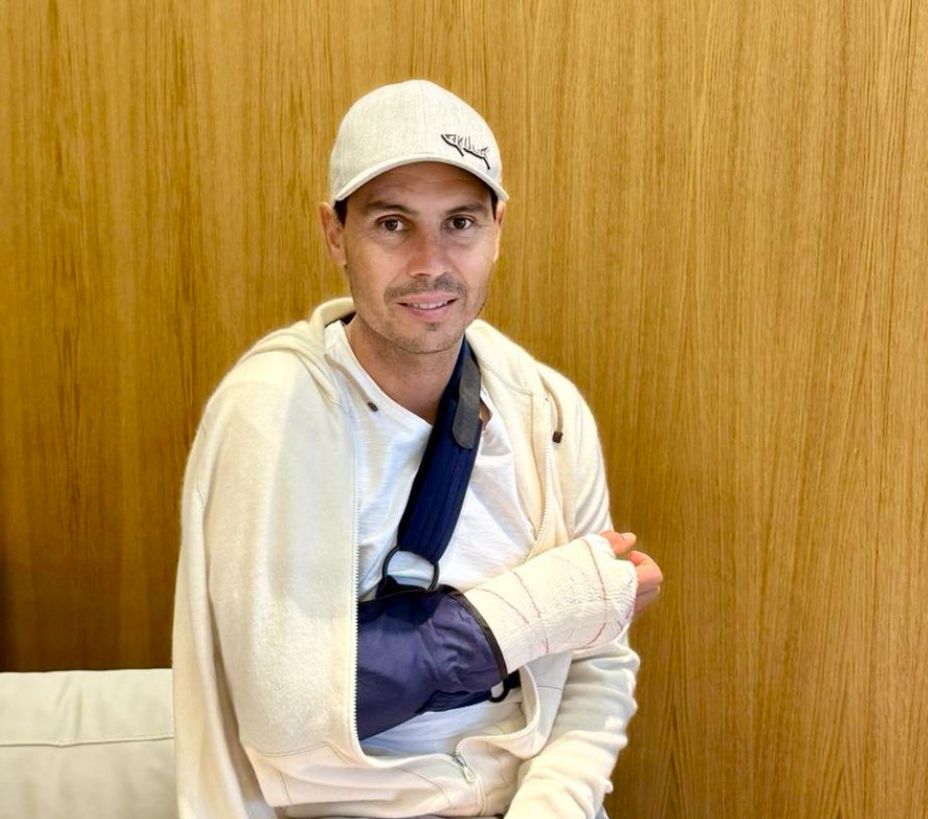 Rafael Nadal in a white outfit and his arm in a sling
