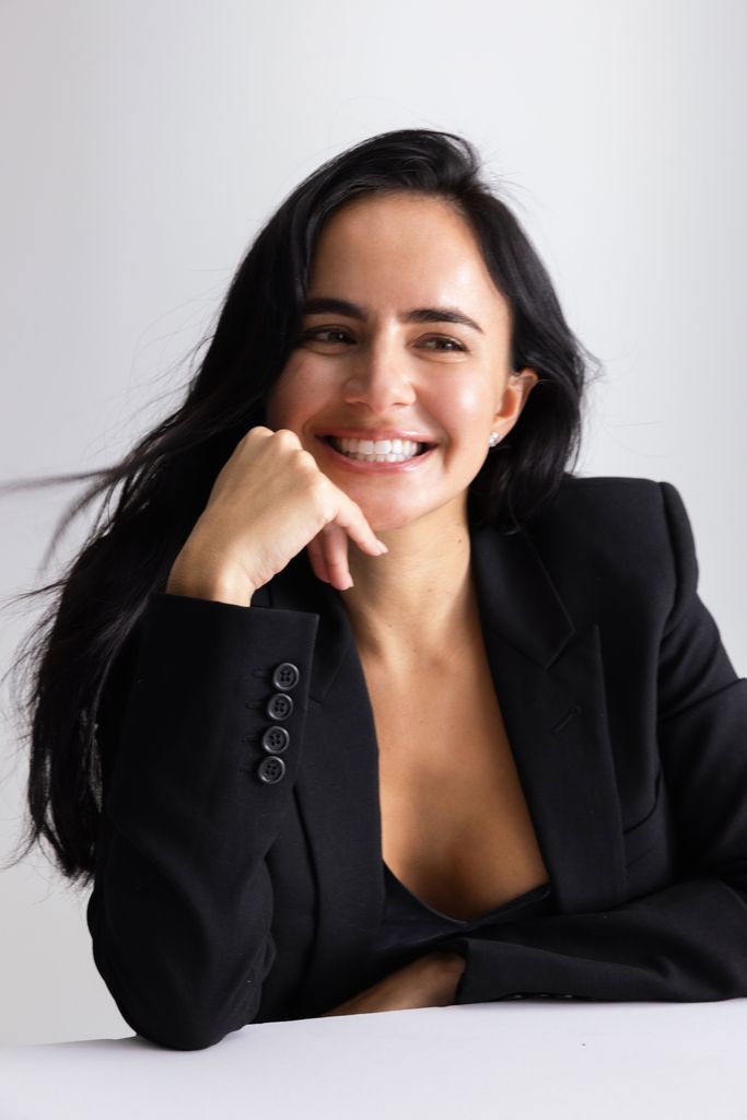 brunette woman smiling with her head resting on her hand 
