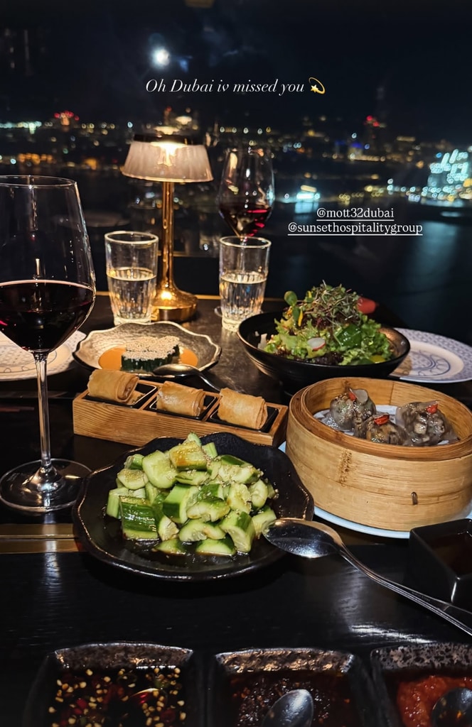 A view of dinner at Mott 32 Dubai showcasing a glass of wine and several Chinese dishes