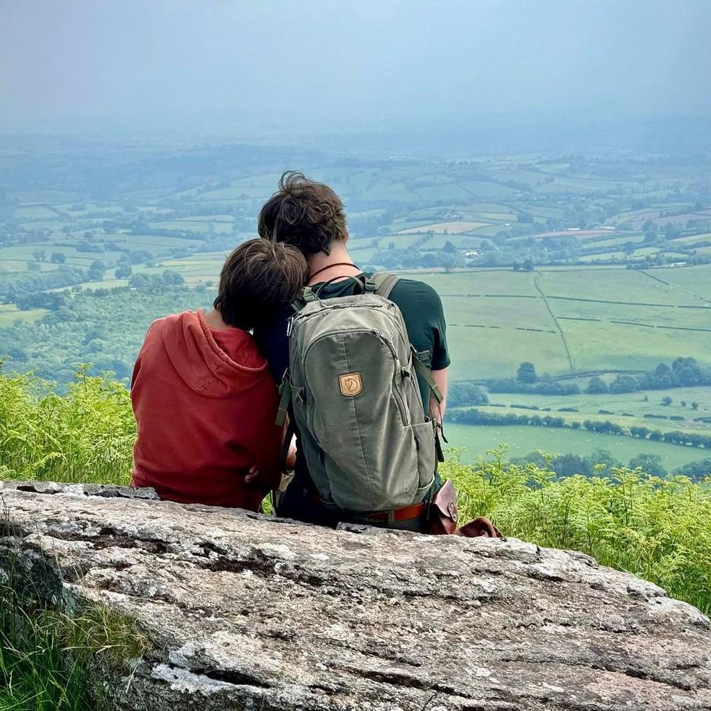 Simon Reeve sitting on a log looking at fields with his son