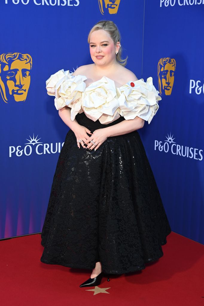 Nicola Coughlan on red carpet in dress with white top and black skirt
