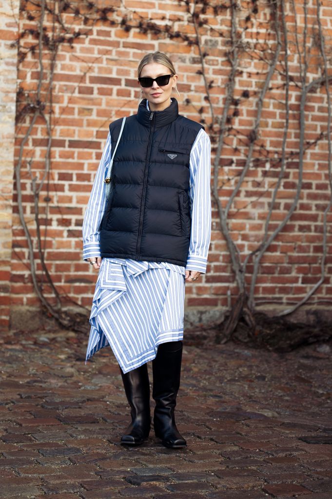 Hollie Mercedes Peters wears white and blue stripped shirt, black puffy Prada vest, light blue bag with a heart accessory and black long boots outside the OpÃ©raSport show during the Copenhagen Fashion Week Autumn/Winter 2025 on January 27, 2025 in Copenhagen, Denmark.