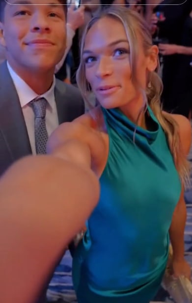 Anna Hall in a green dress and Ben Shelton in a suit take a selfie for social media while attending black tie sports event