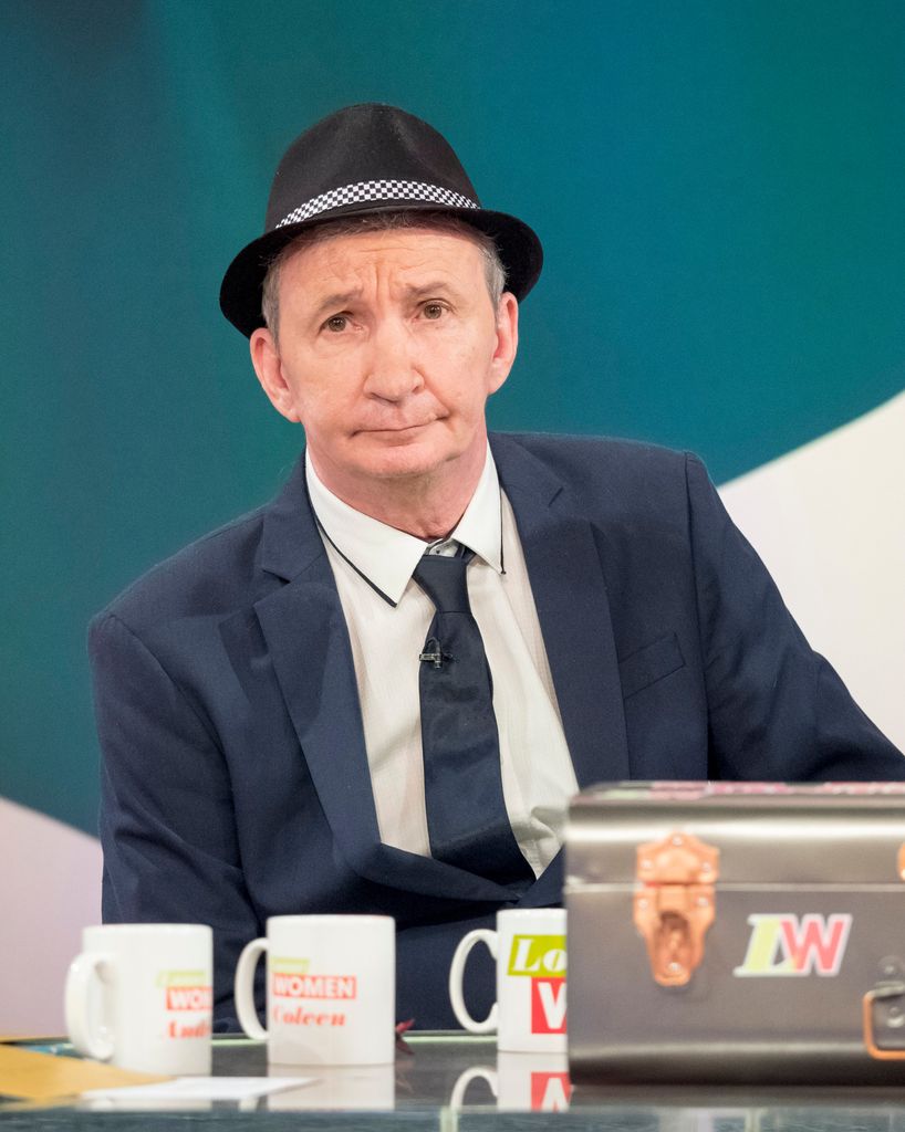 man in suit and hat in tv studio