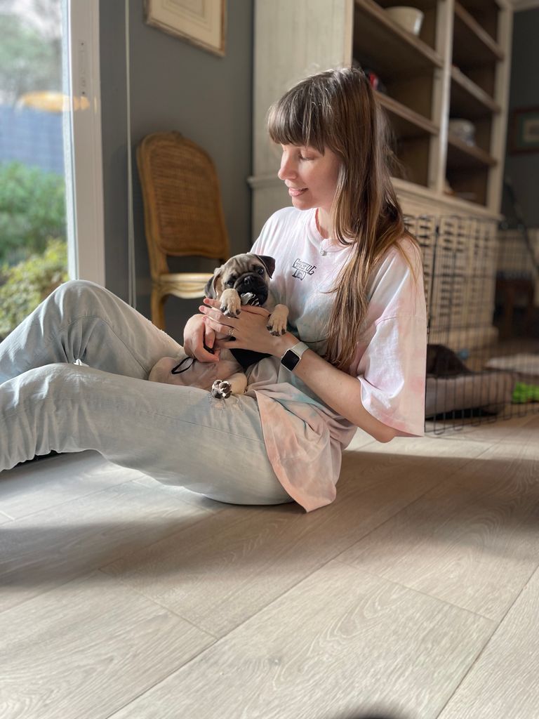 Woman sitting on the floor cuddling her pug