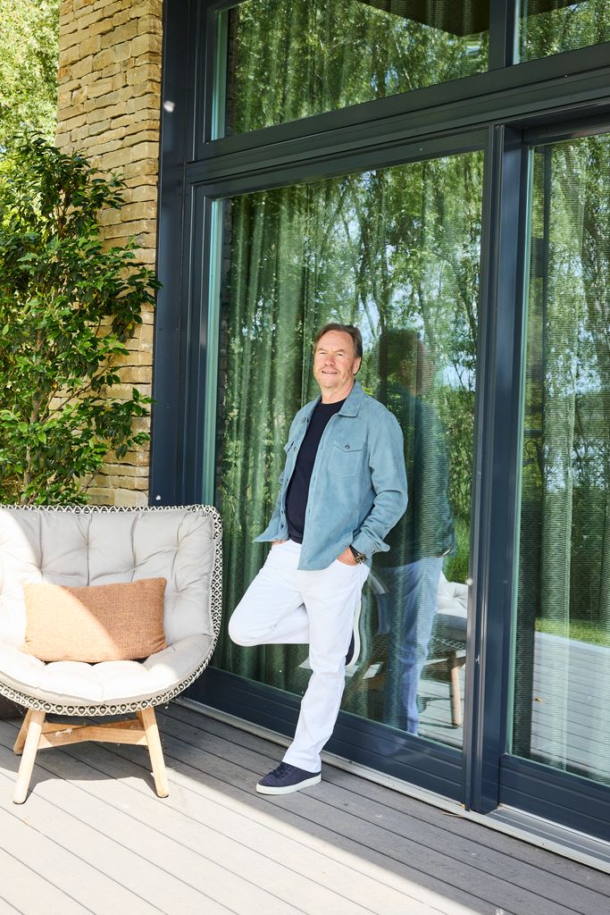 man leaning against a window in casual clothes 