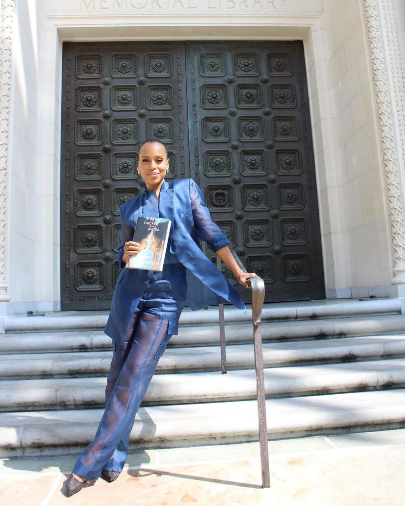 Kerry Washington poses on the stairs with a book Thicker than Water in his hand.