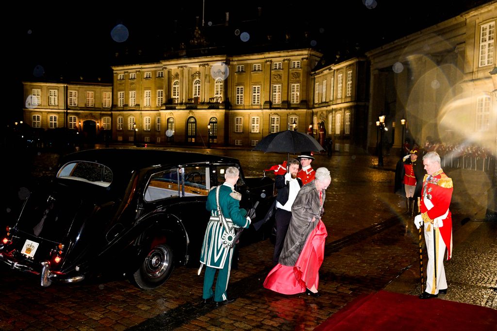 Queen Margrethe II of Denmark in a red dress walking from a car