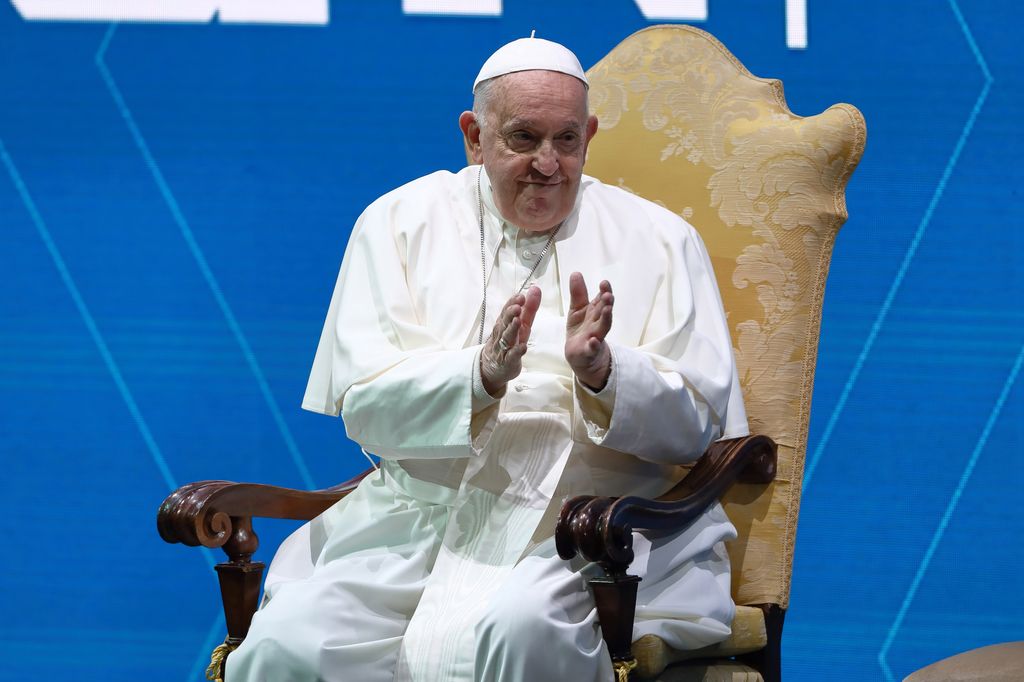 Pope Francis applauding while sitting in a gold chair