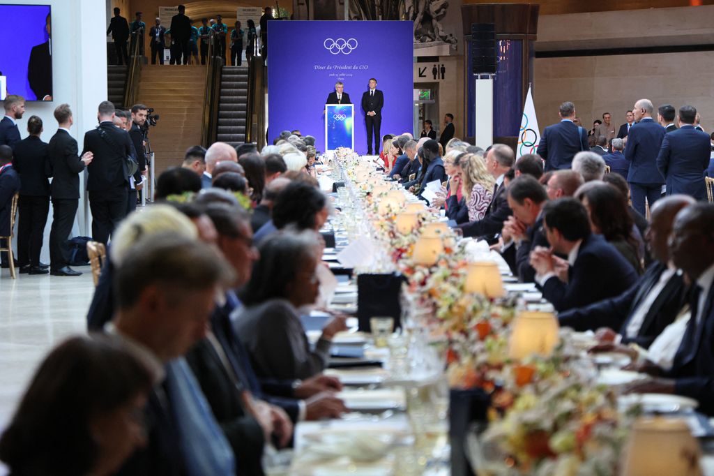 President of the International Olympic Committee (IOC) Thomas Bach (Rear C on stage) flanked by French President Emmanuel Macron, delivers a speech as Heads of States, Sports personnalities and guests attend a gala dinner hosted by the International Olympic Committee (IOC) and the French Presidency in the atrium of the Louvre Museum in Paris, on the eve of the opening ceremony of the Paris 2024 Olympic Games, on July 25, 2024. (Photo by Ludovic MARIN / POOL / AFP) / RESTRICTED TO EDITORIAL USE - MANDATORY MENTION OF THE ARTIST UPON PUBLICATION - TO ILLUSTRATE THE EVENT AS SPECIFIED IN THE CAPTION (Photo by LUDOVIC MARIN/POOL/AFP via Getty Images)