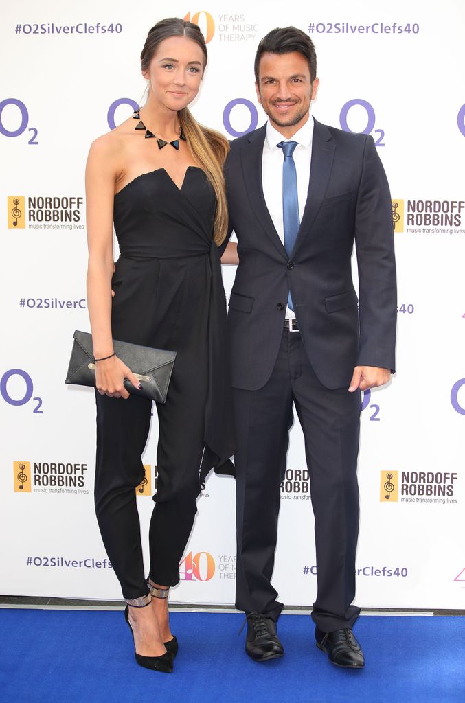 Emily Andre in a white dress standing with Peter Andre in a suit