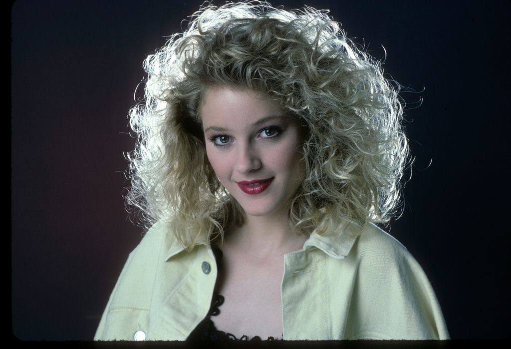 Teri Polo porte une veste jaune et regarde la caméra.