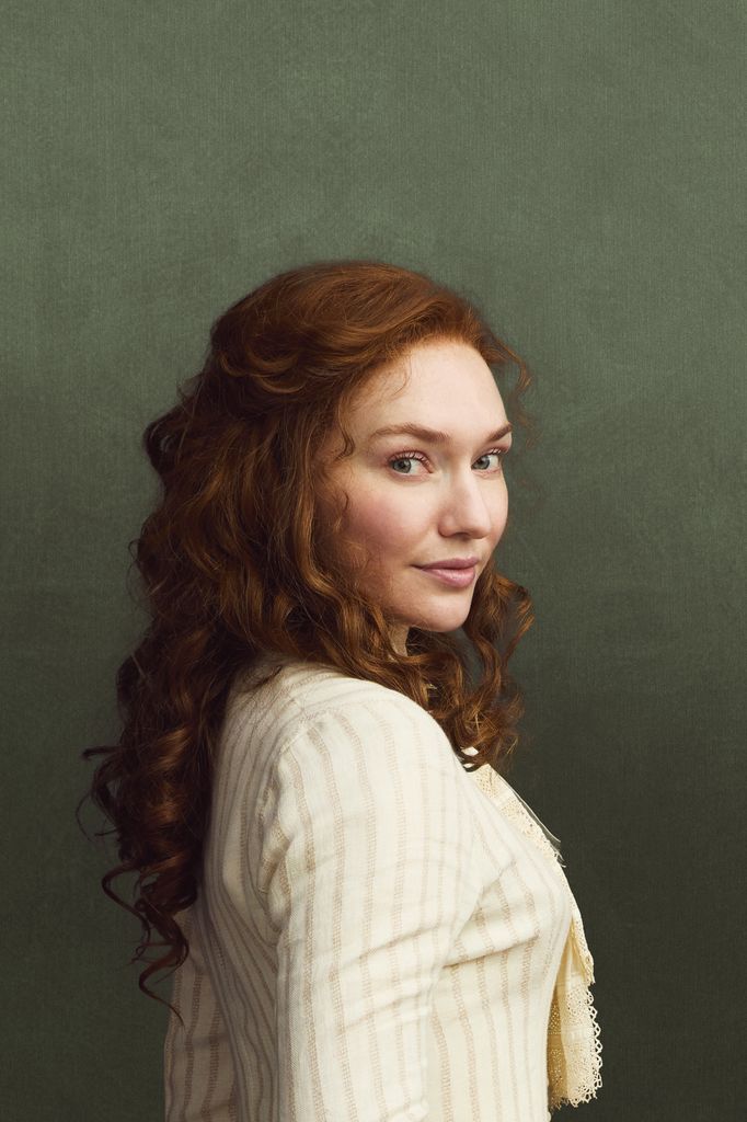 woman with red curly hair against green background