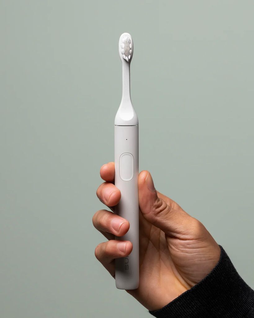 White SURI toothbrush being held by a hand