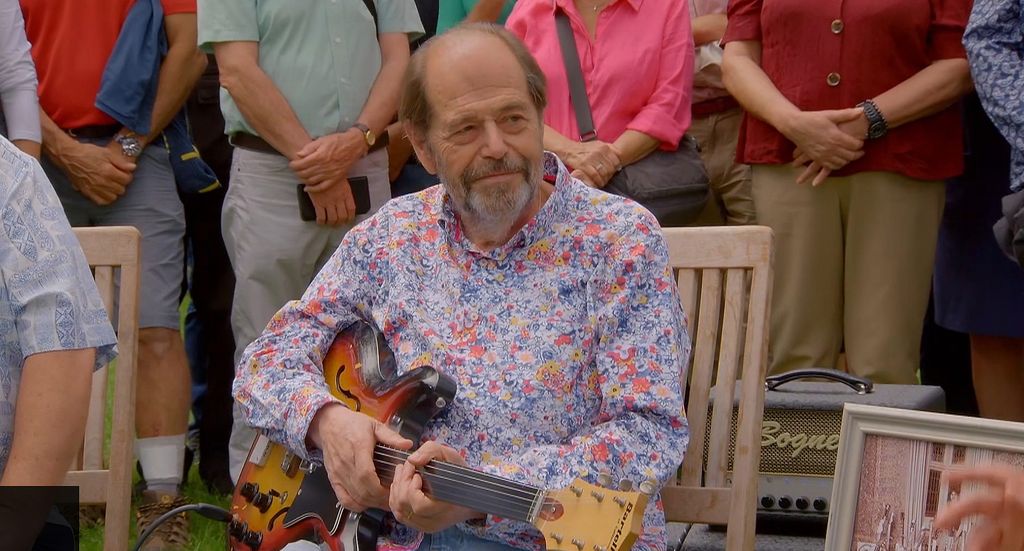 Seller Ray holding a guitar that belonged to John Lennon and George Harrison