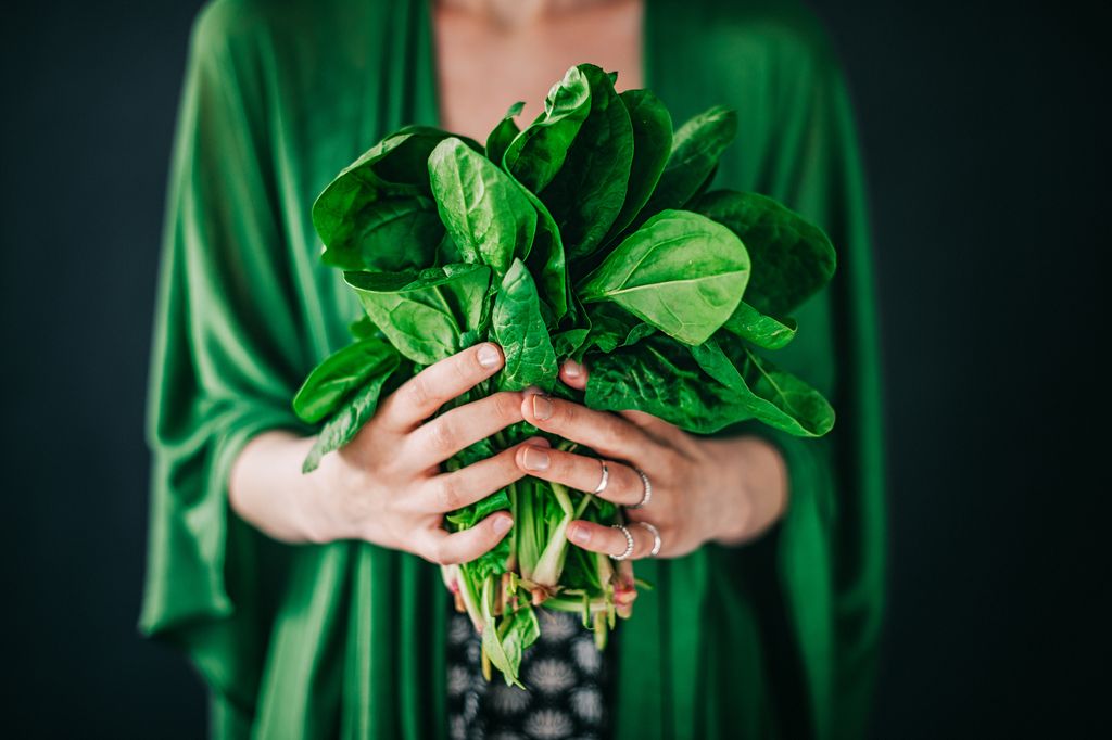 Young woman holding spinach leaf salad