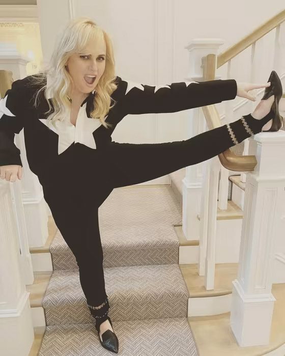 rebel wilson stretching her leg on her stairs