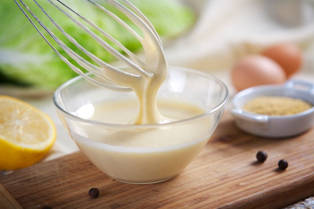 Homemade mayonnaise being whipped in a glass bowl