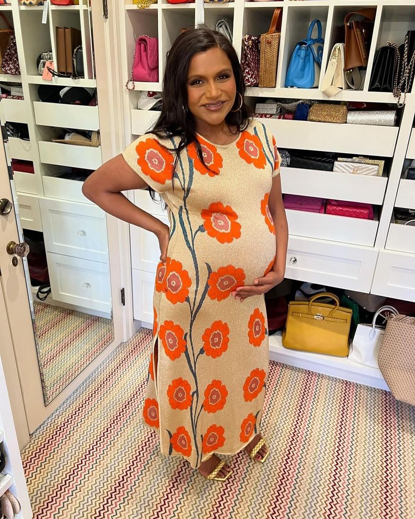 Mindy Kaling holding her baby bump in her walk in wardrobe