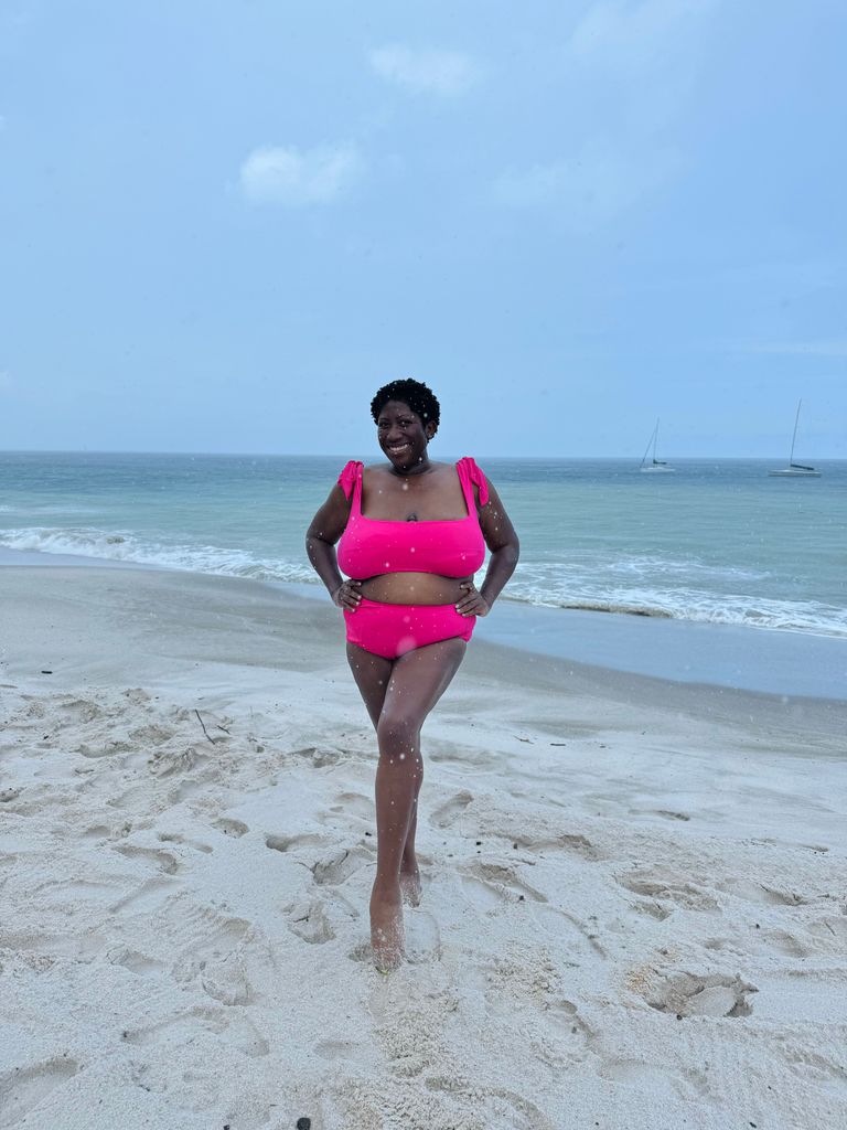Woman smiling on the beach in a bright pink bikini 