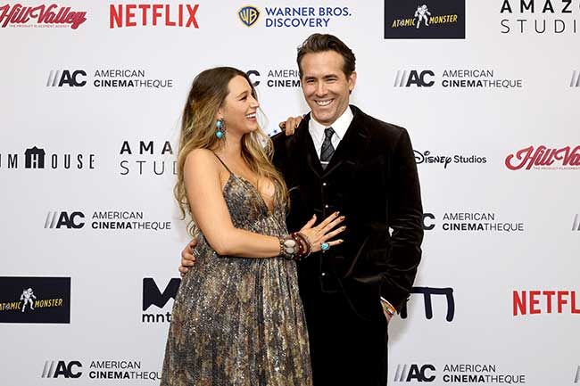A pregnant Blake with Ryan on a red carpet, both smiling at each other